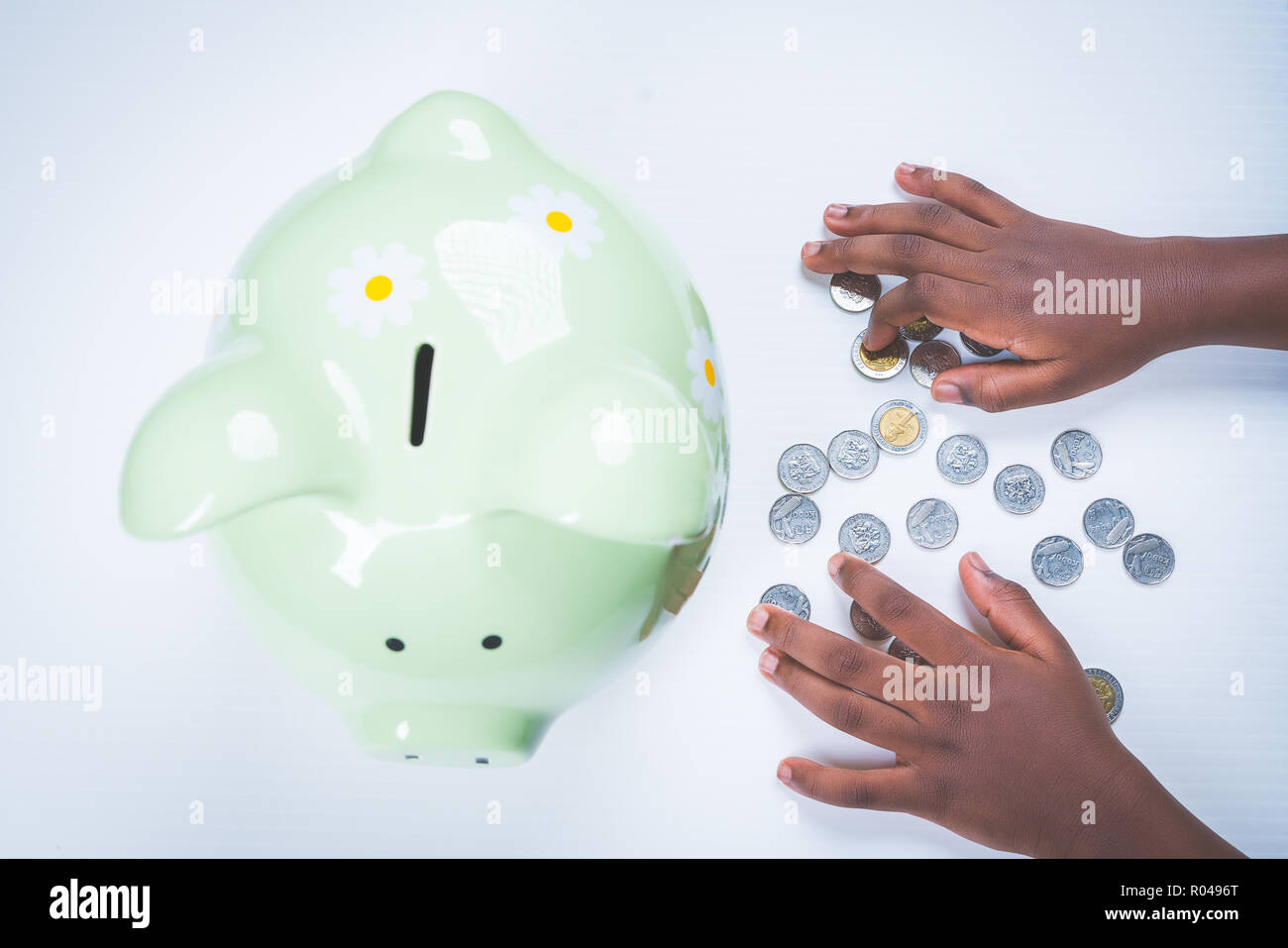 African American girl hands counting coins by piggy bank. Stock Photo