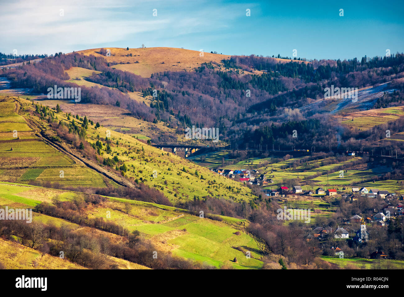 village in a valley. november weather. grassy rural fields on hills above settlement. lovely sunny day. Stock Photo