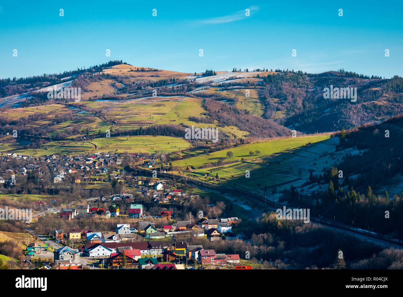 village in a valley. november weather. grassy rural fields on hills above settlement. lovely sunny day. Stock Photo