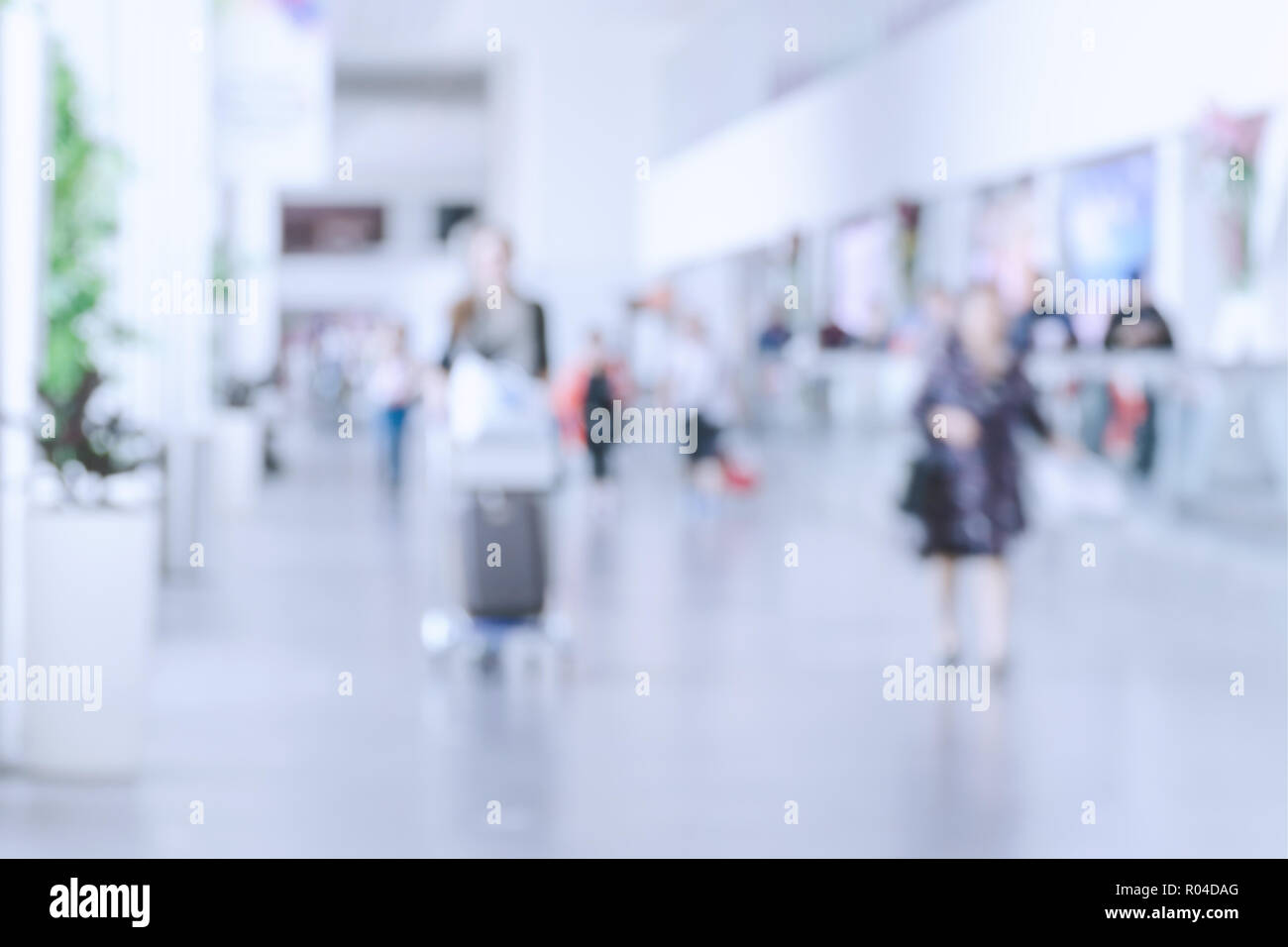 Blurred photo with people at airport, defocused silhouettes indoors, unrecognizable persons, abstract background with crowd, motion blur. Stock Photo