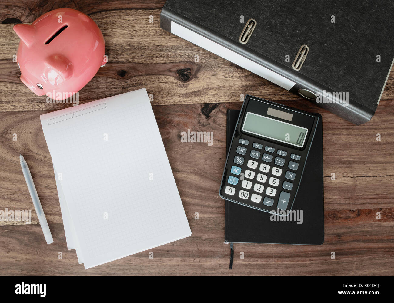 file folder, note pad, calculator and piggy bank on table Stock Photo