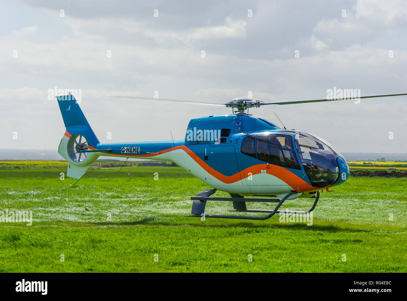 Eurocopter EC120 Colibri G-HEHE helicopter of HE Group Ltd landing at former Leysdown Airfield, Kent, UK for centenary of first British flight Stock Photo