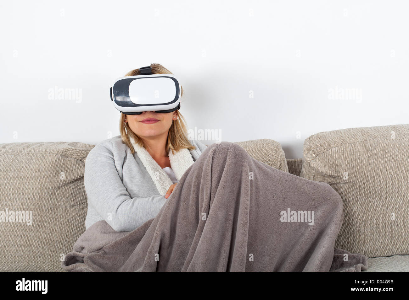 Woman watching a 3d virtual reality video with headset while relaxing on  the sofa Stock Photo - Alamy