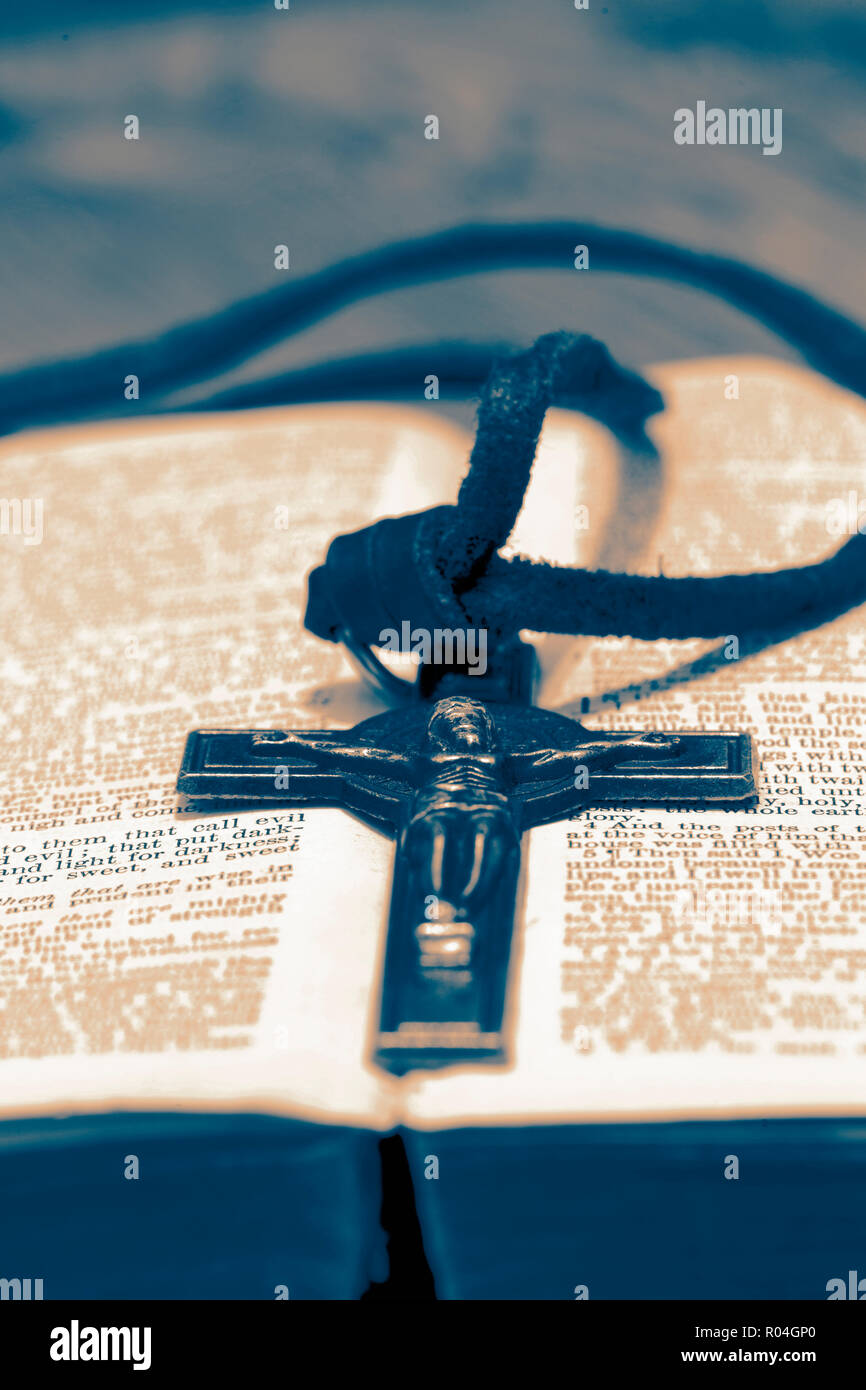 Crucifix necklace on a bible page on wood background with toning Stock Photo