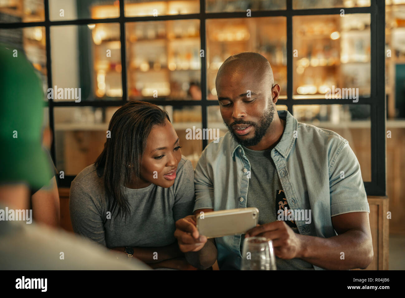 Two friends sitting in a bar looking at cellphone photos Stock Photo