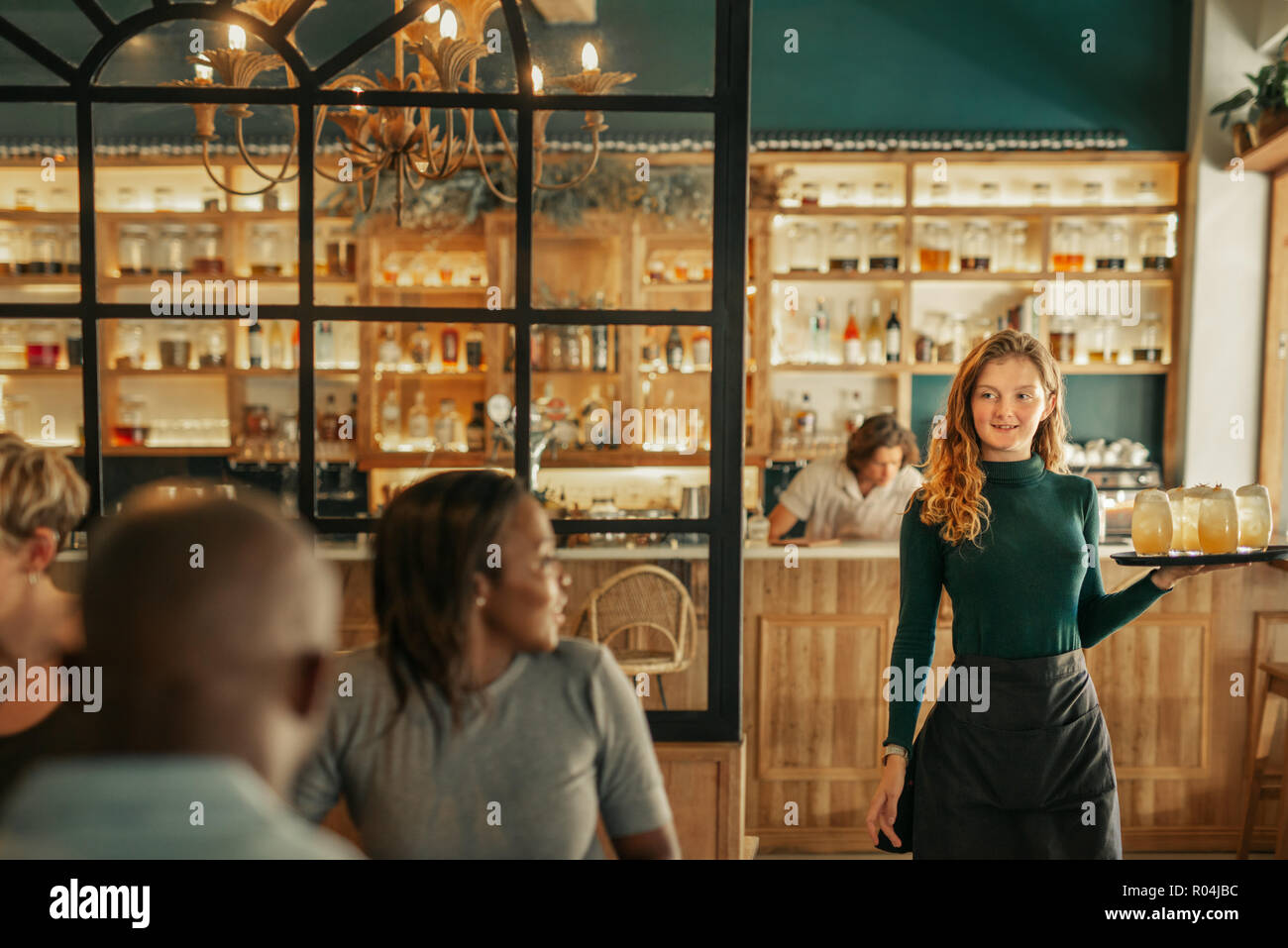 Smiling waitress bringing drinks to people sitting in a bar Stock Photo