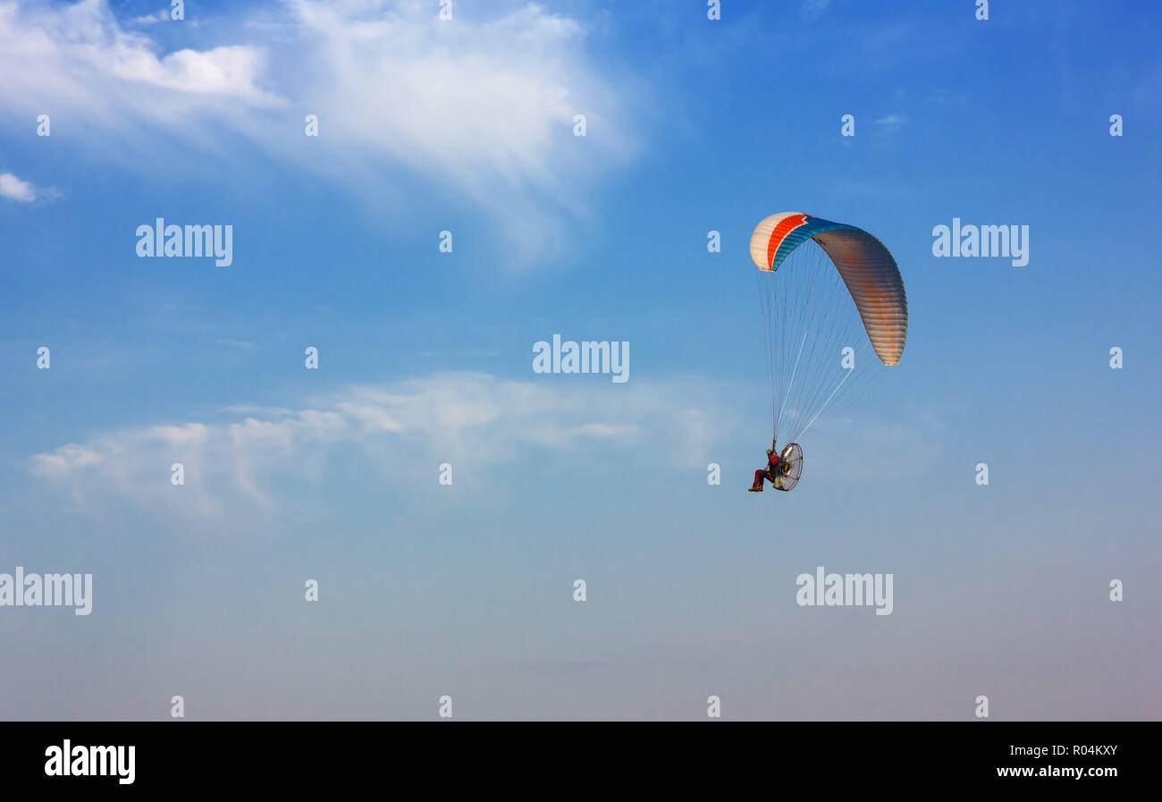 Powered paraglider flying in a clear blue sky Stock Photo