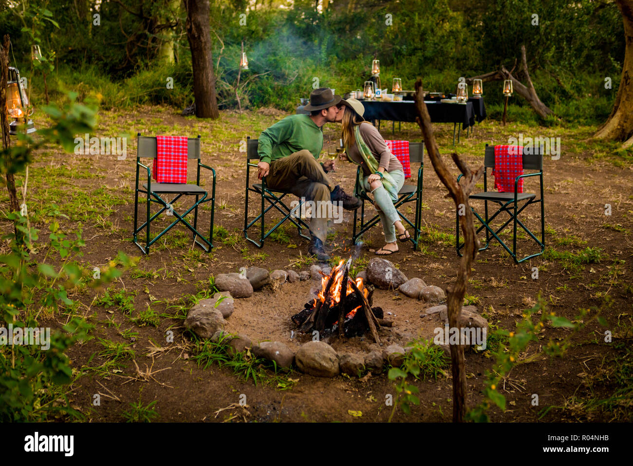 Couple kissing by a safari camp campfire in Zululand, South Africa, Africa Stock Photo