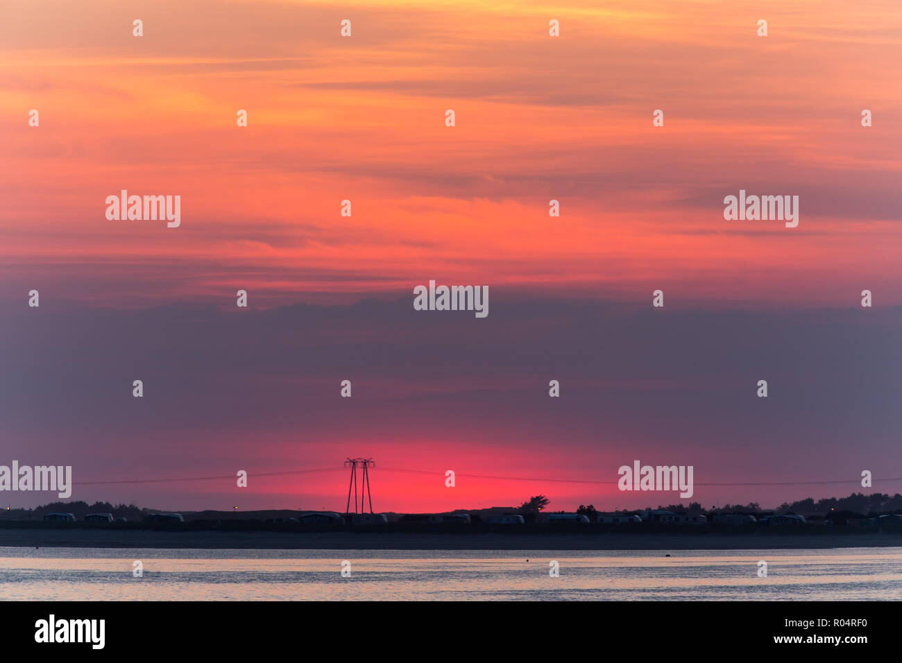 Red sunset over Carnac beach with electric pylons, Brittany, France Stock Photo