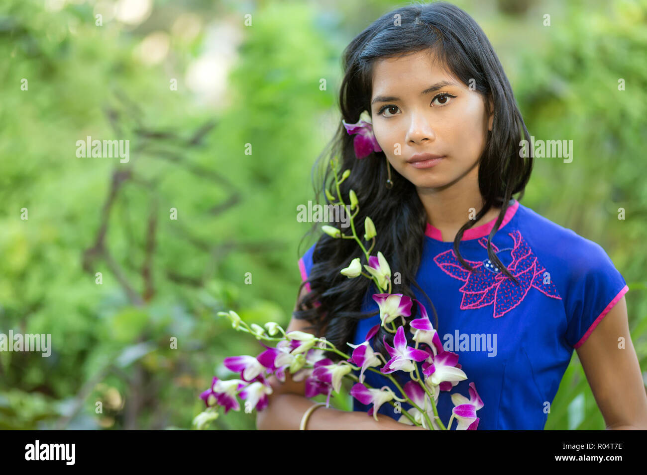 Pretty Vietnamese Woman Wearing A Traditional Ao Dai Dress And Holding Orchid Flower Bunch Stock