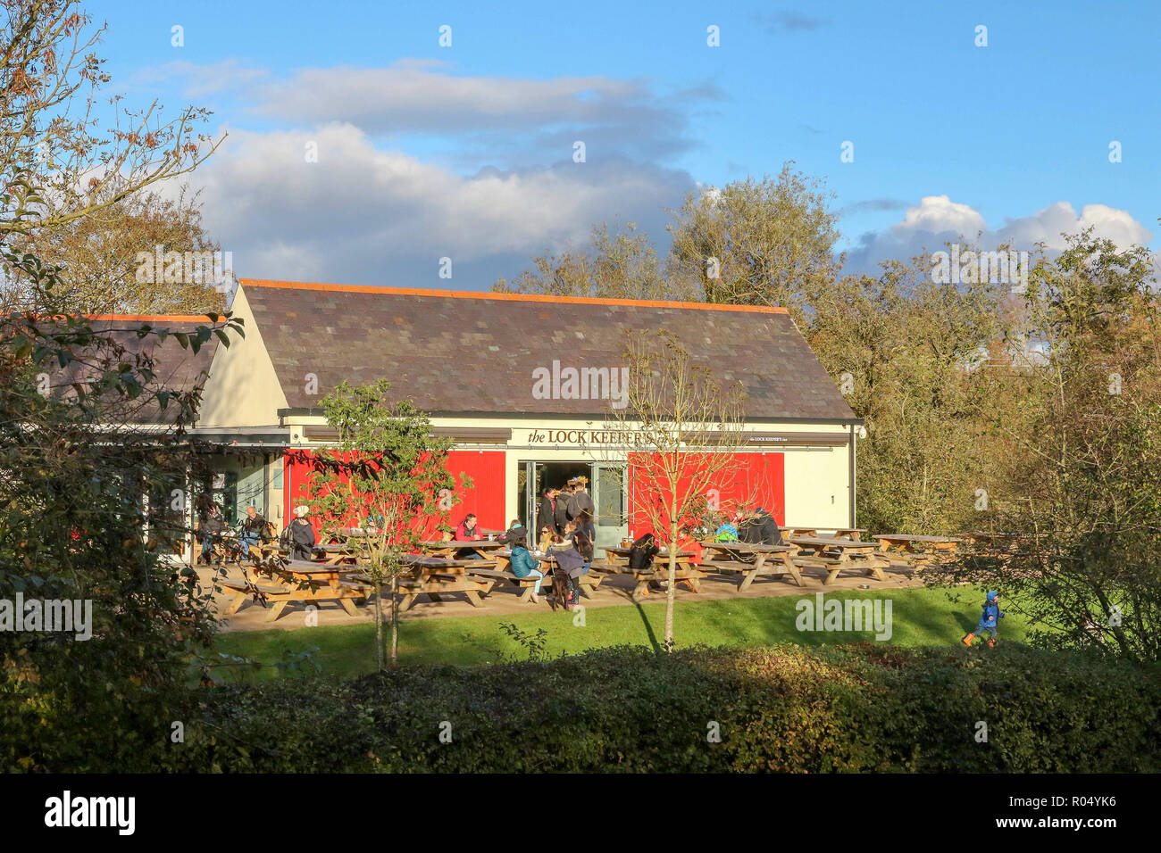 Lagan Towpath, Belfast, Northern Ireland. 01 November 2018. UK weather - a bright but cold day saw autumn colours at their finest along the towpath. With half-term it was a day to be wrapped up and out. People sitting outside The Lock Keeper's Inn, River Lagan, Belfast  Credit: David Hunter/Alamy Live News. Stock Photo