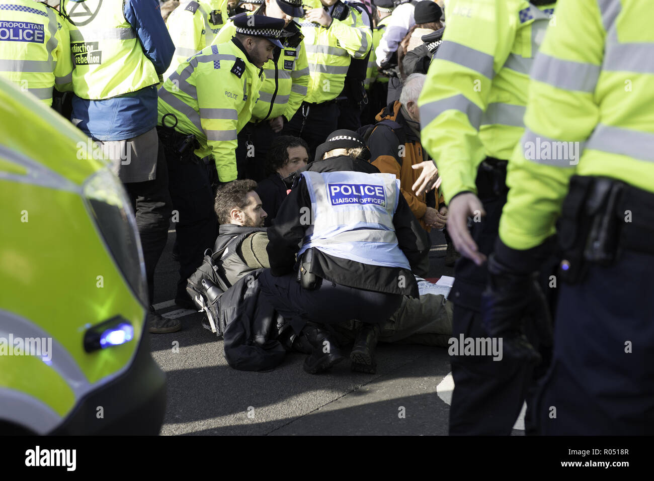 London, Greater London, UK. 31st Oct, 2018. Police officers are seen holding an activist who was lying from the road during the protest.The newly formed Extinction Rebellion group, concerned about climate change, calls for a peaceful mass civil disobedience to highlight politicians' lack of commitment and action regarding environmental issues. Activists gathered at the Parliament Square and blocked the road for two hour. The protest included speakers such as Greta Thunberg, Caroline Lucas, and George Monbiot. According to Extinction Rebellion 15 people were arrested in the p Stock Photo