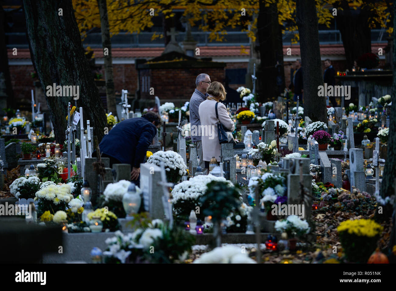 Krakow, Poland. 1st Nov, 2018. People are seen standing while praying next to a grave at the Rakowicki Cemetery during the celebrations.All Saints Day, also known as The Day of the Dead, is a Roman Catholic day of remembrance of friends and loved ones who have passed away. Credit: Omar Marques/SOPA Images/ZUMA Wire/Alamy Live News Stock Photo