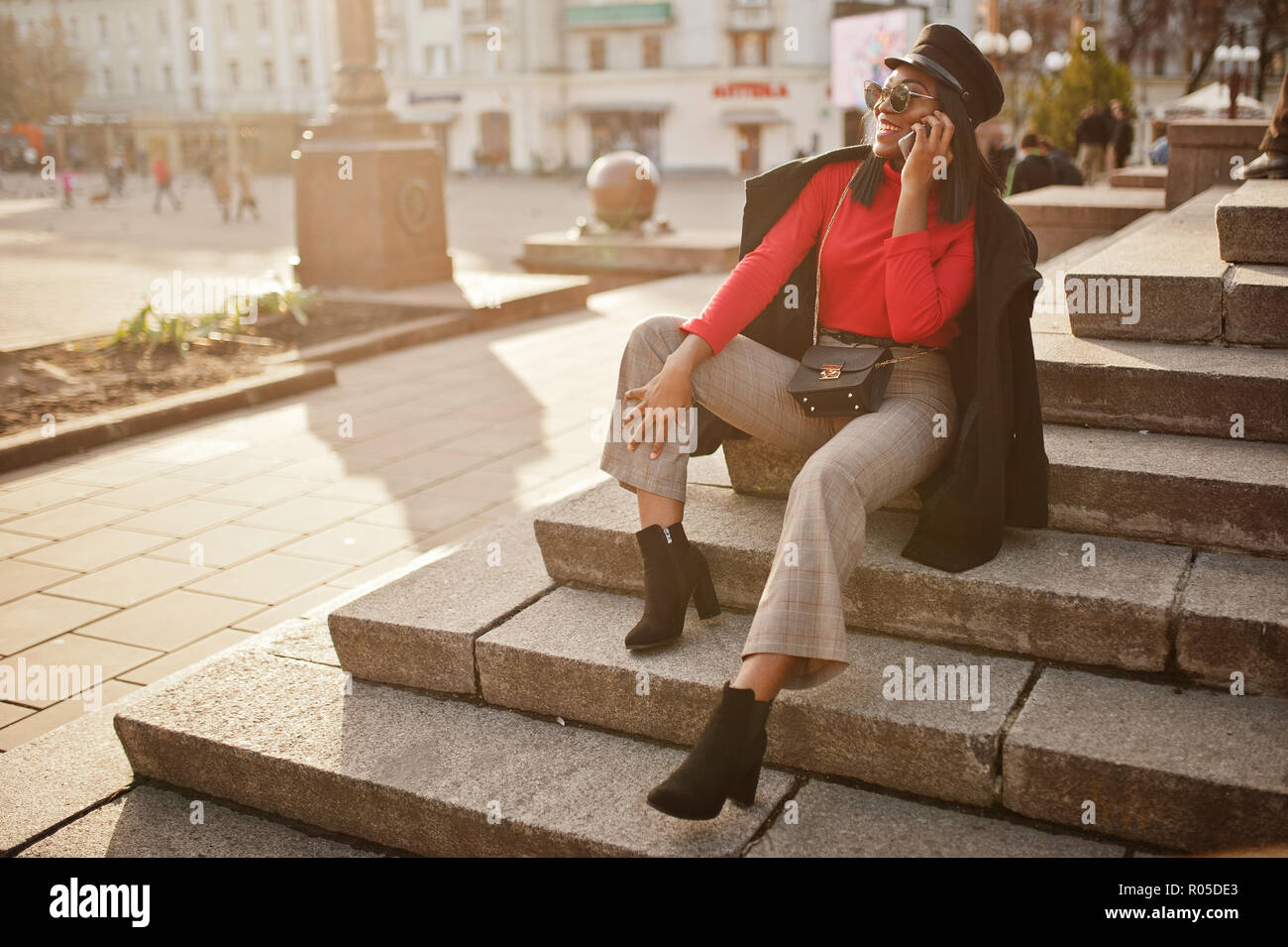 African american fashion girl in coat and newsboy cap, sunglasses posed