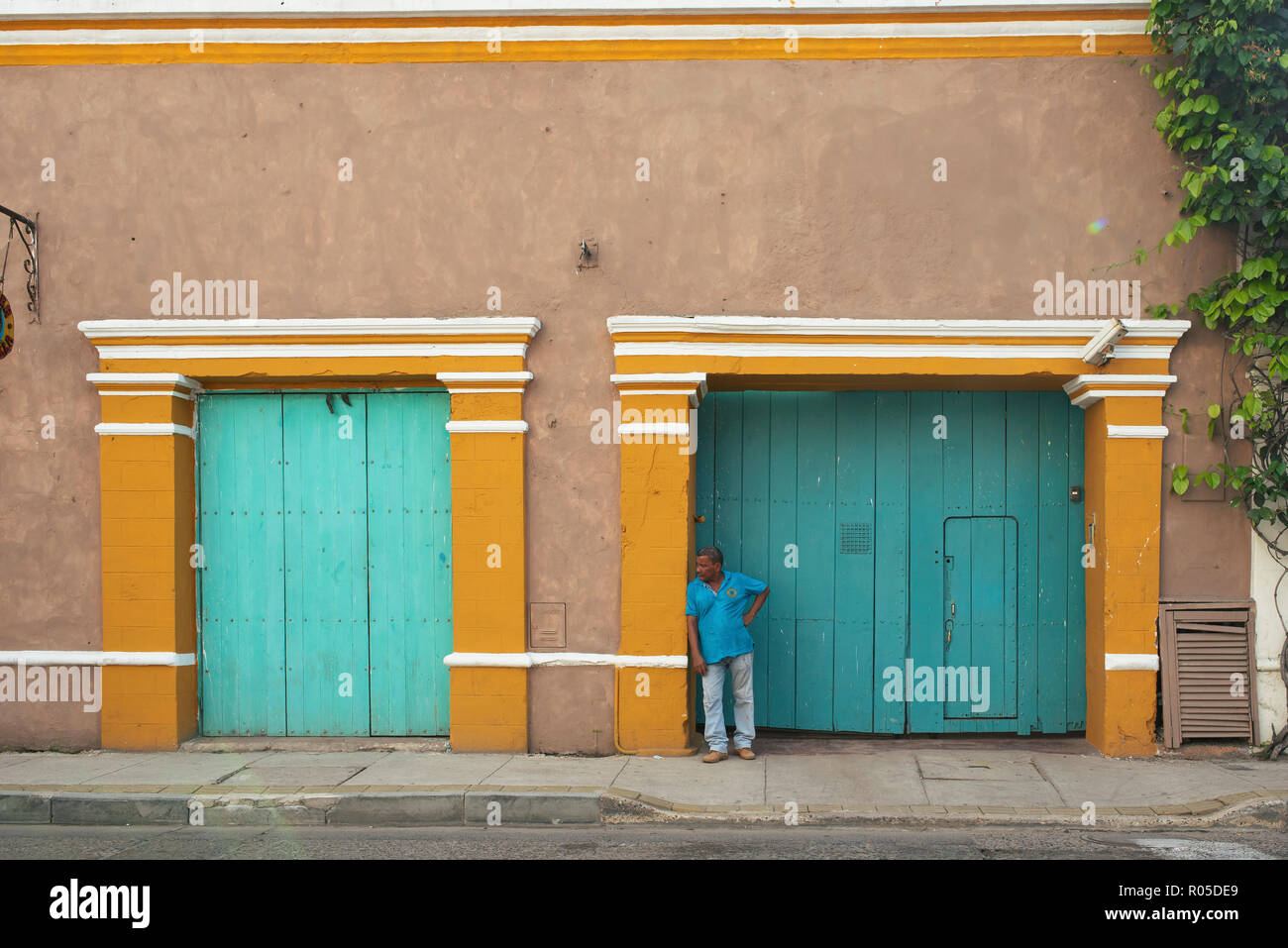 Latino man watching the world go by outside a colourful building. Daily life in Getsemani, Cartagena de Indias, Colombia. Sep 2018 Stock Photo