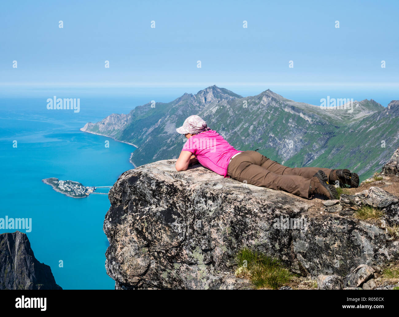 Woman looks over fjord Örnfjord towards island Husöy, top of mountain Grytetippen, island Senja, Troms, Norway Stock Photo