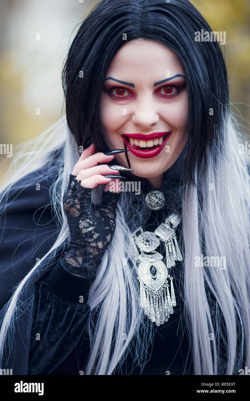 Image of smiling vampire girl with stream of blood near her mouth, red ...