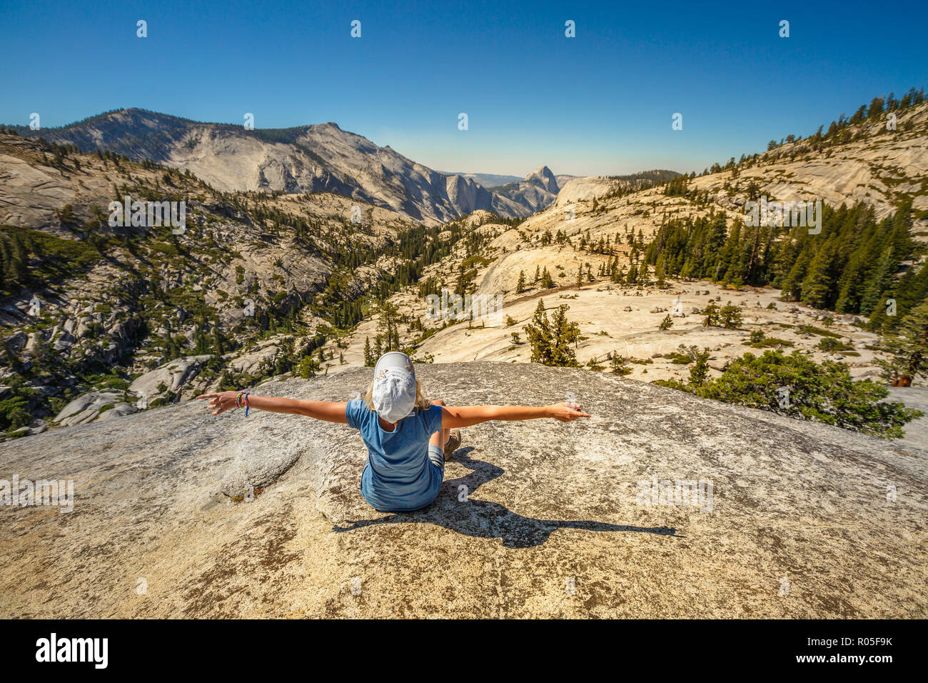Hiking enthusiastic woman relaxing at Olmsted Point and looking the north side Half Dome. Tired hiker resting lying down outdoors taking a break from hiking. Yosemite National Park, California, USA Stock Photo