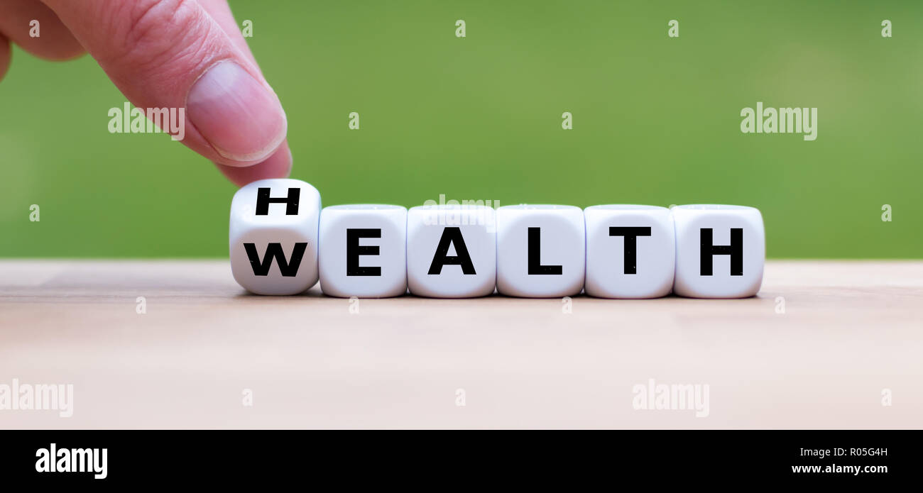 e:Hand is turning a dice and changes the word 'Health' to 'Wealth' Stock Photo