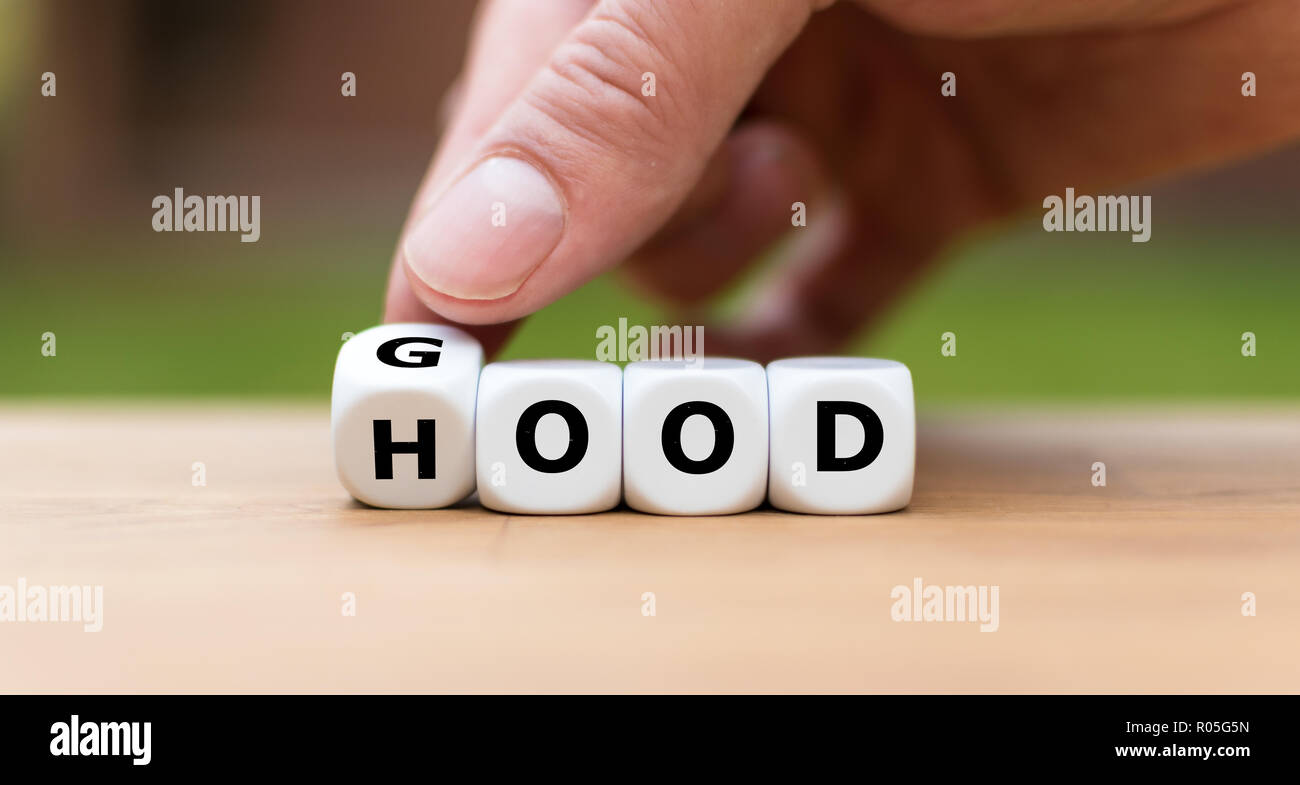 Hand is turning a dice and changes the word 'good' to 'hood' Stock Photo