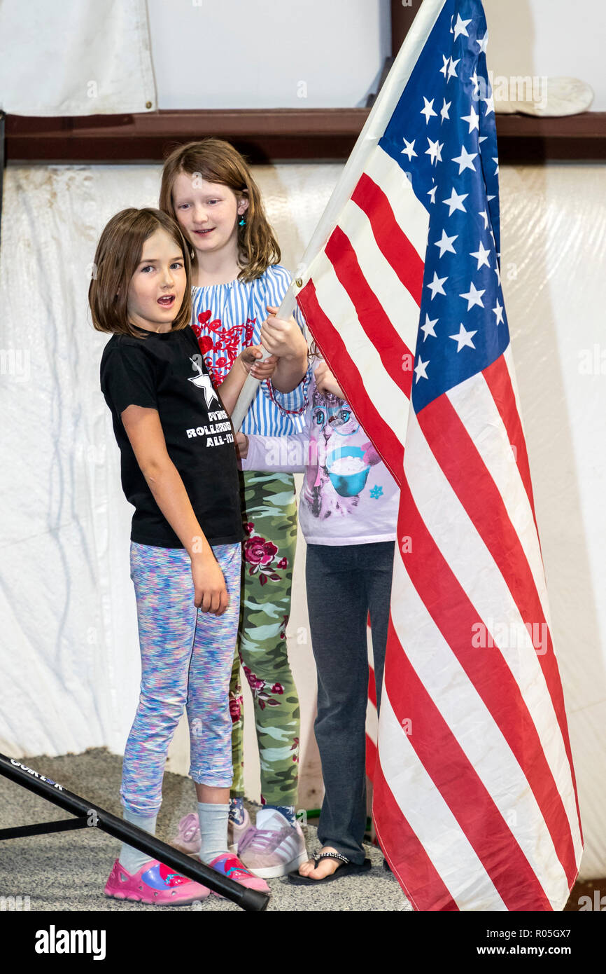 Two young girls hold the American Flag during the National Anthem at a sporting event Stock Photo