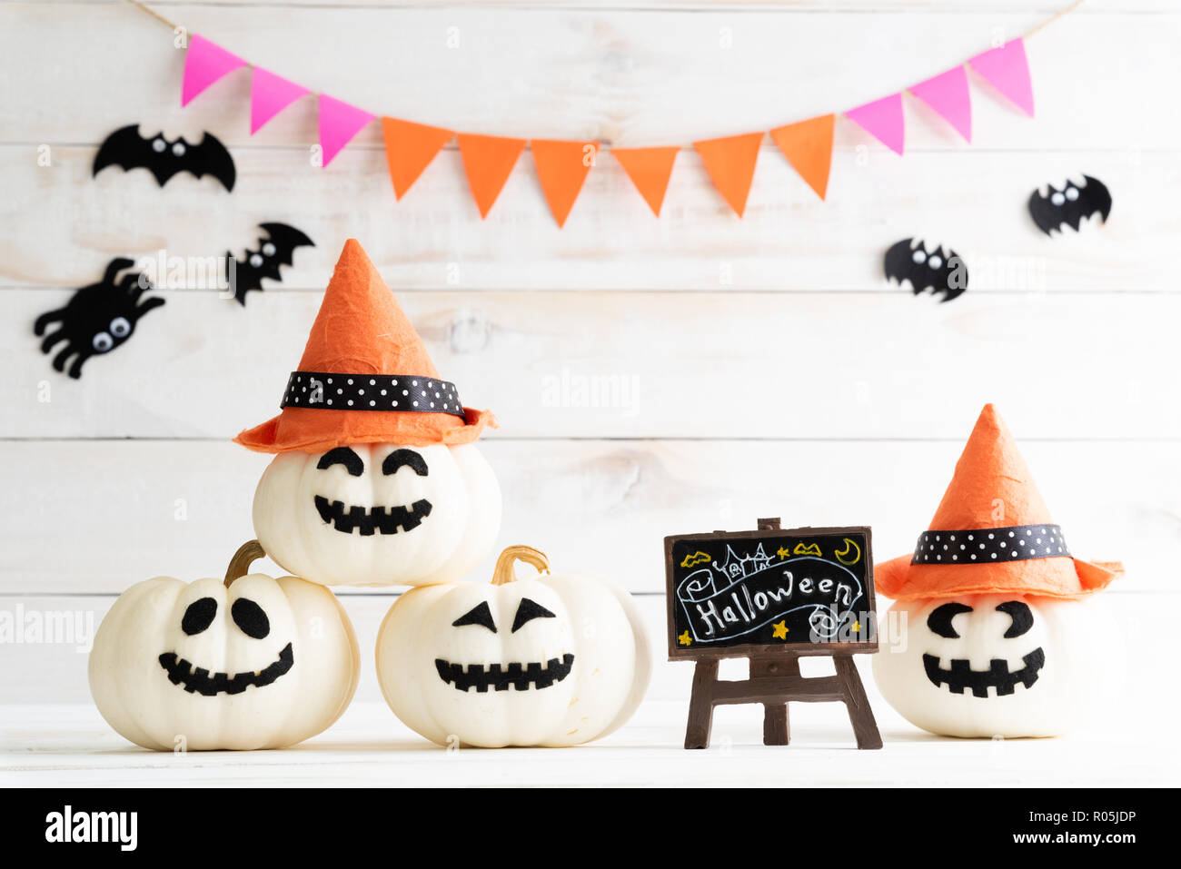 White and yellow ghost pumpkins with witch hat on white wooden borad ...