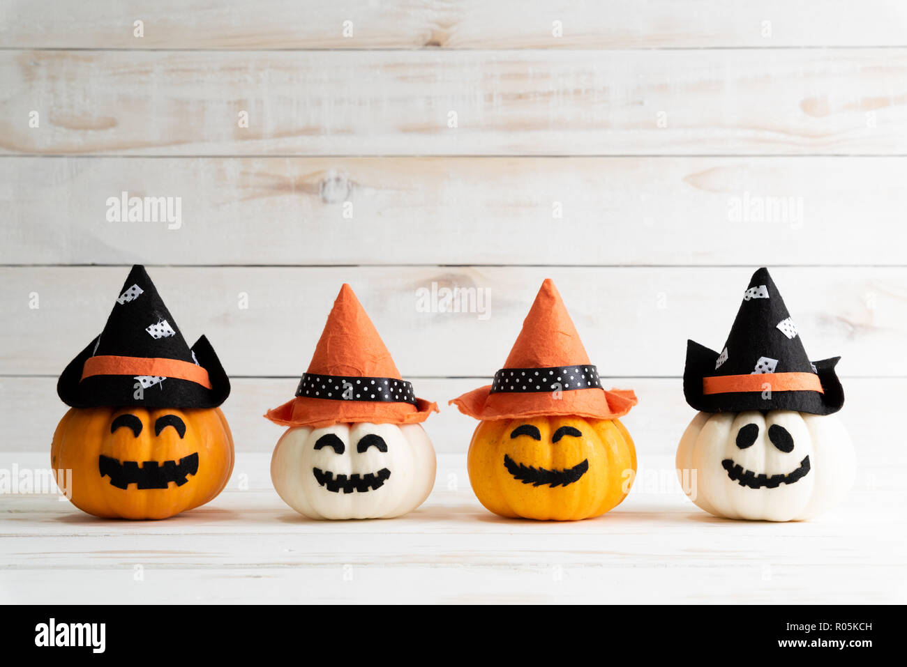 White and yellow ghost pumpkins with witch hat on white wooden borad ...