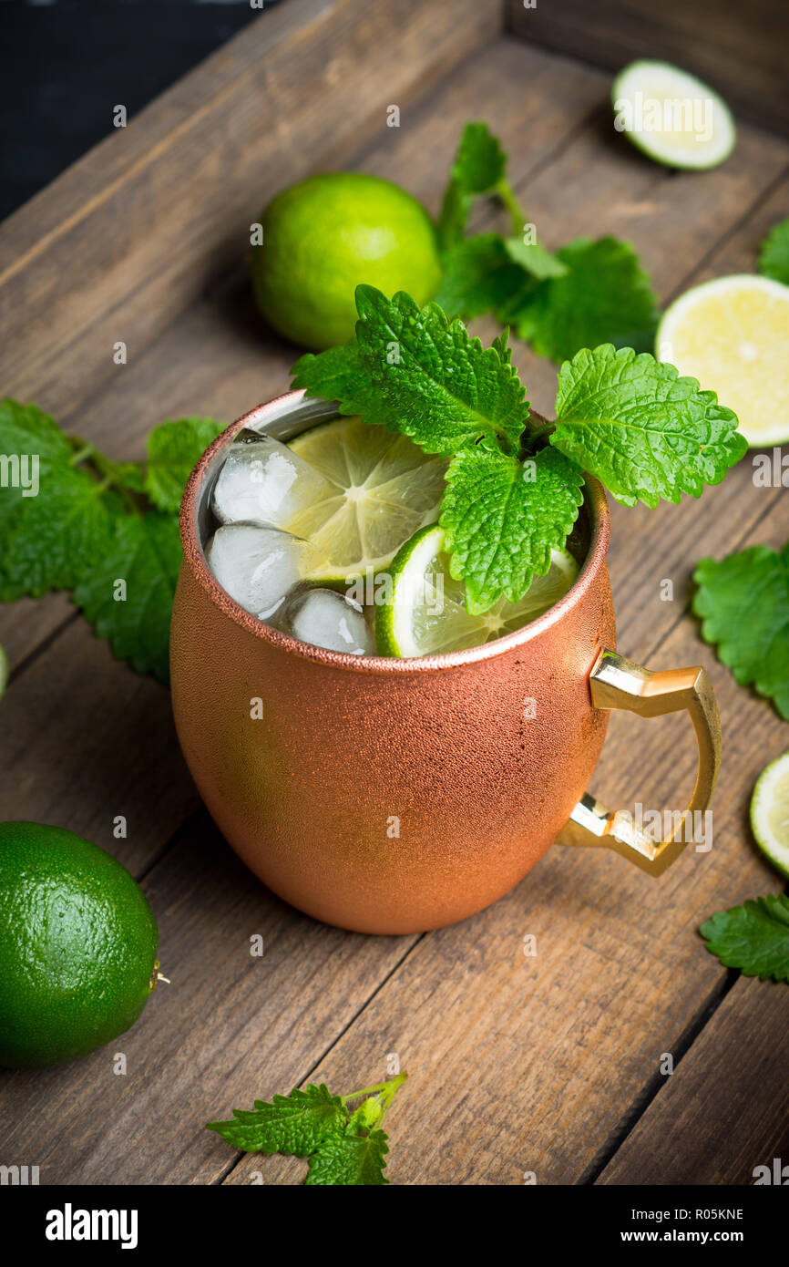 Cold Moscow Mule cocktail in copper mug on the rustic background