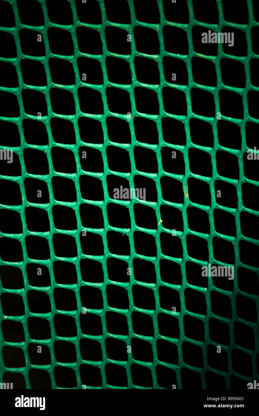 Green plastic mesh illuminated by the sun in the center and in shadow at the corners Stock Photo