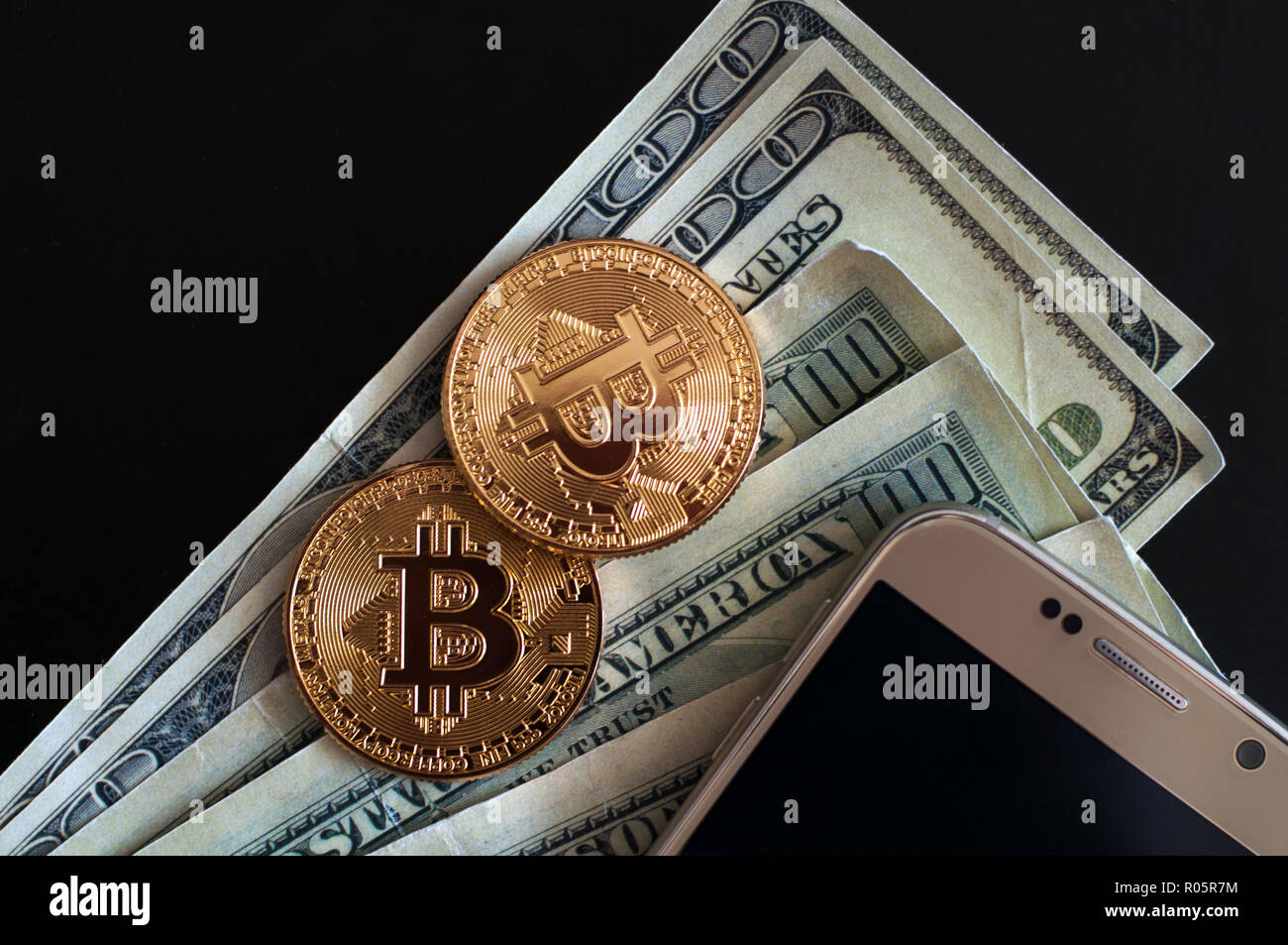 two golden coins of bitcoin and dollars and mobile phone on black  background Stock Photo - Alamy