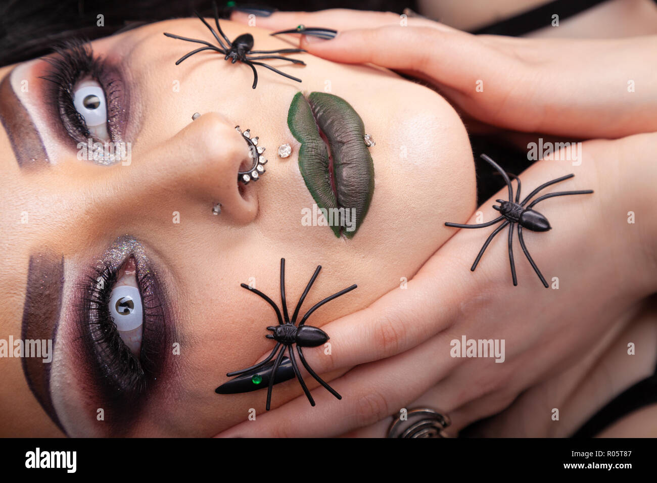 Close up of a gothic looking woman's face with fake plastic spiders. Stock Photo