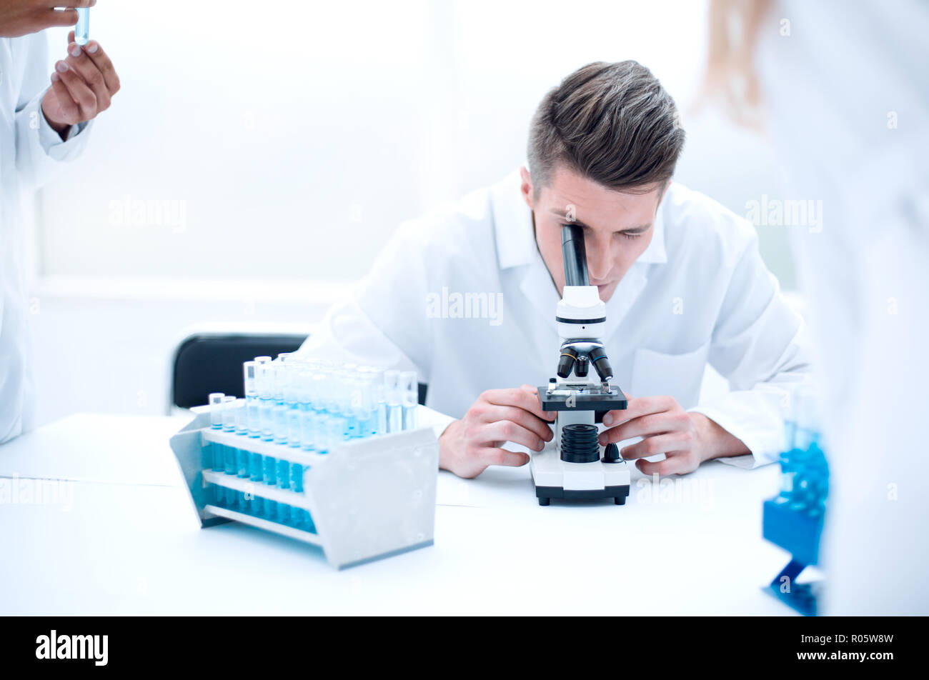 Young scientist looking through a microscope in a laboratory. Young scientist doing some research. Stock Photo