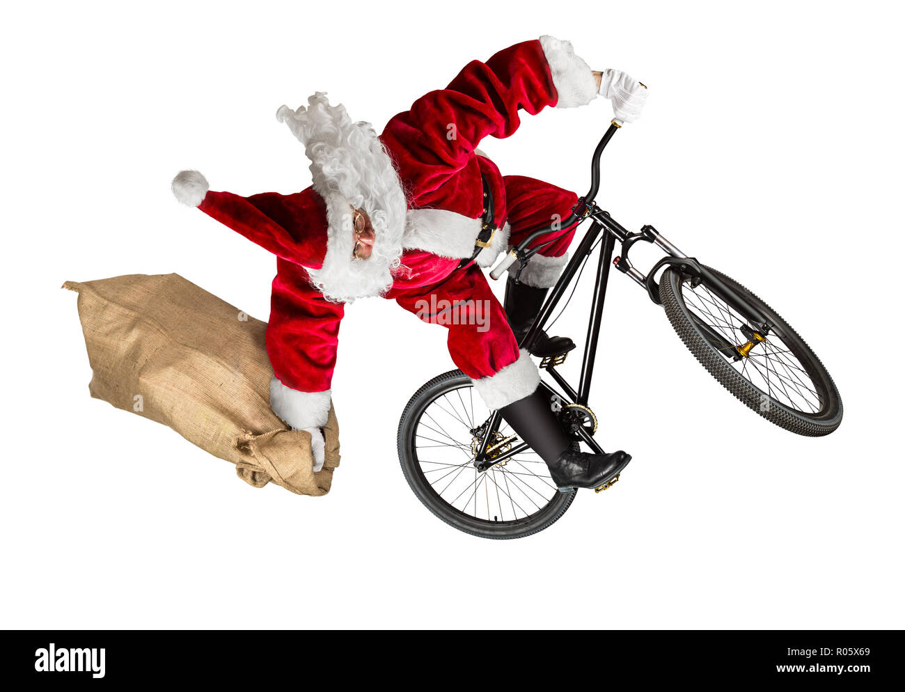 crazy santa claus jump on dirt mountain bike with jute burlap bag isolated abstract christmas funny sport white background Stock Photo