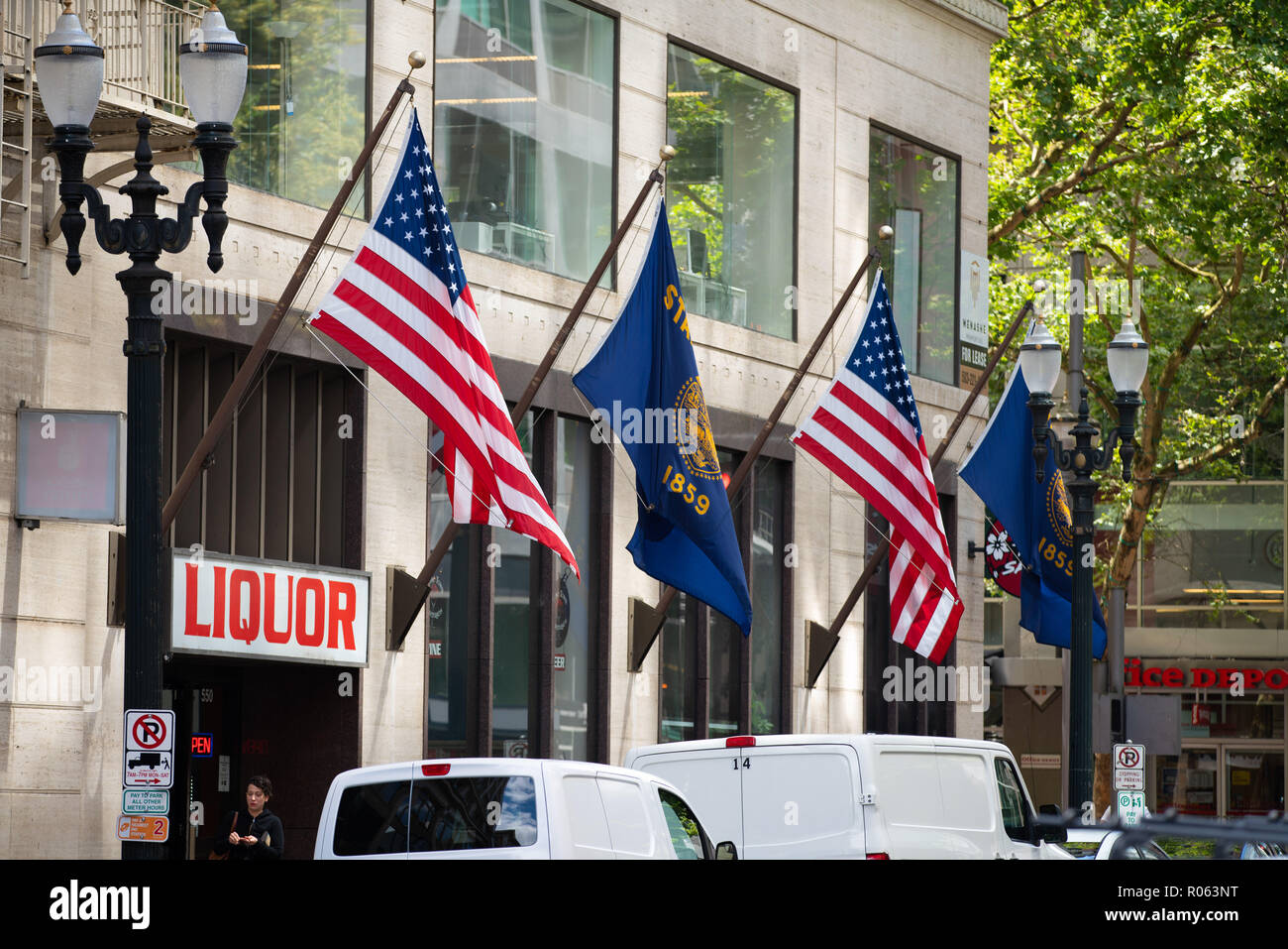 Portland, OR / USA - June 21 2018: American and Oregon flags hanging outside of a liquor store in downtown. Stock Photo
