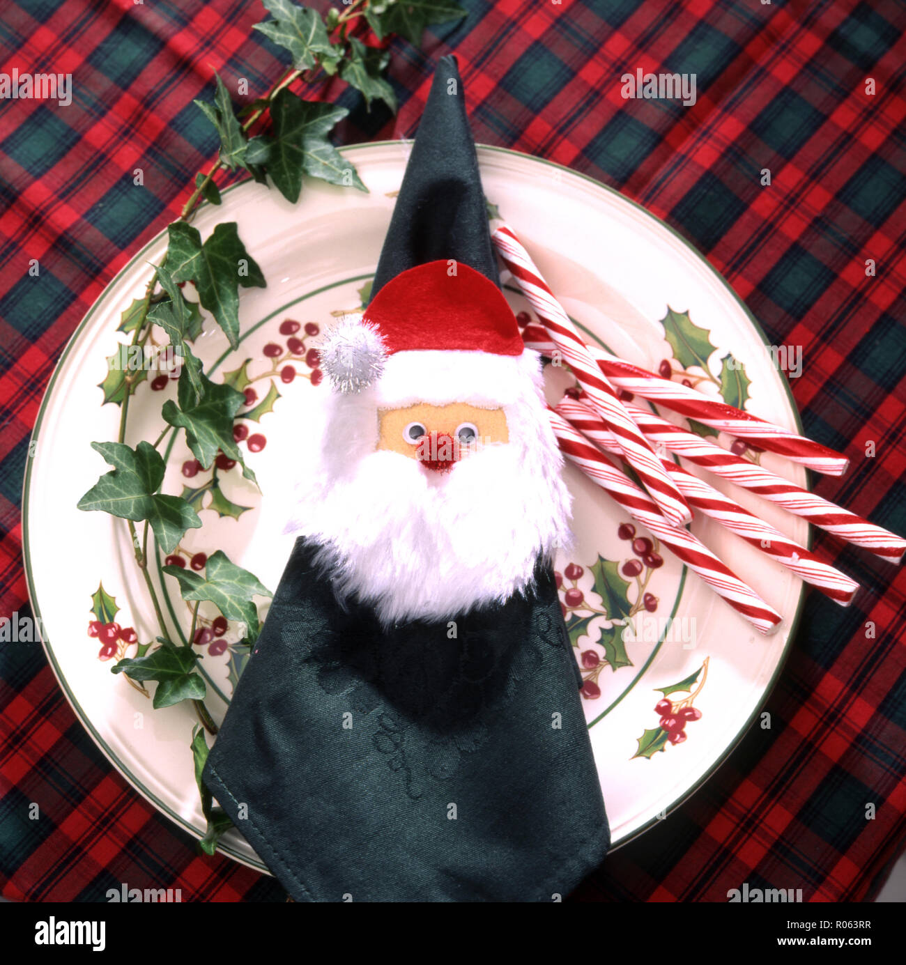 CHRISTMAS PLATE SETTING FEATURING FATHER CHRISTMAS NAPKIN HOLDER, CANDY CANES AND IVY Stock Photo