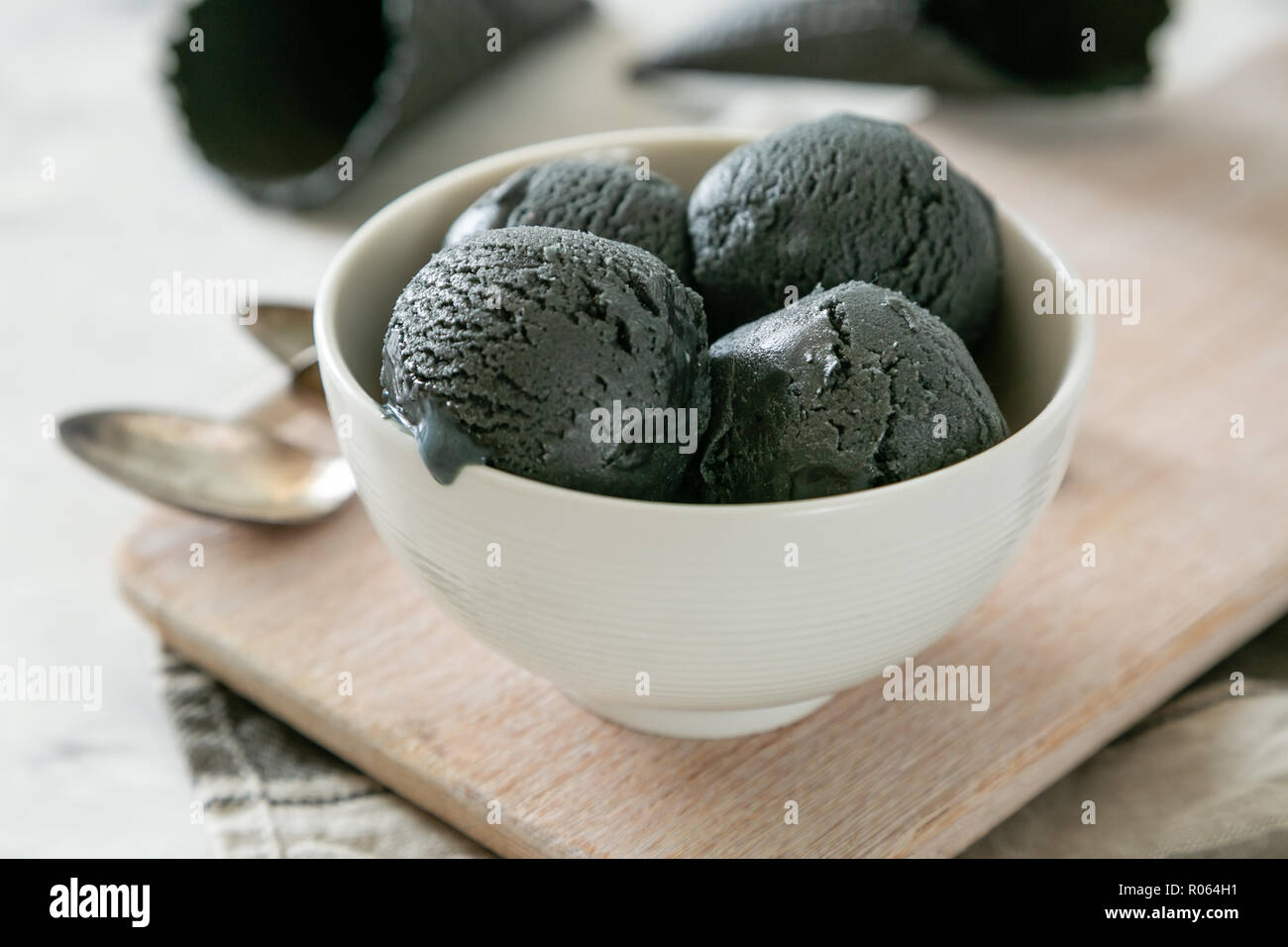 Activated charcoal ice cream with cones on marble background, copy