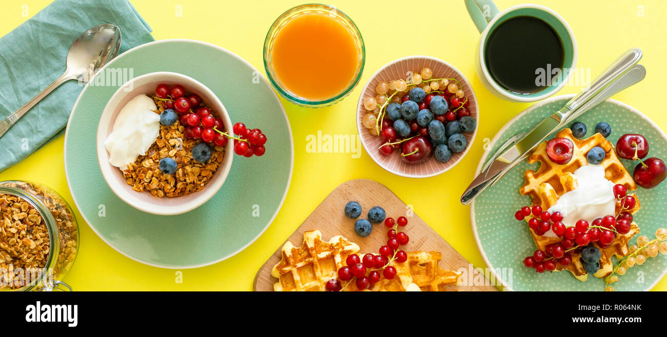 Breakfast with waffles, wipped cream, berries and granola, bright ...