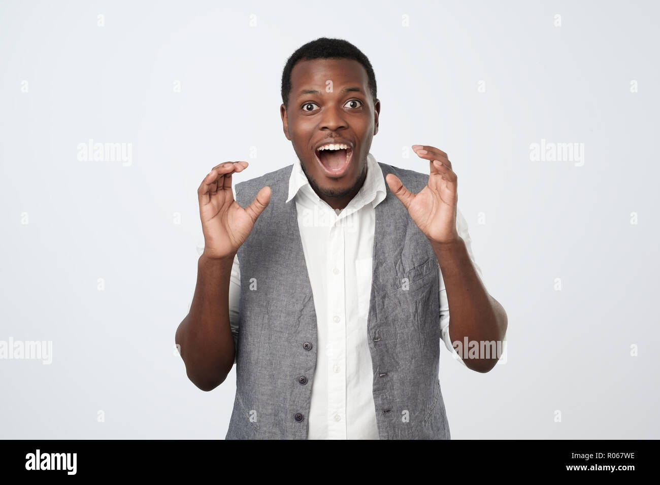 Portrait of an african excited casual man standing with raised hands ...
