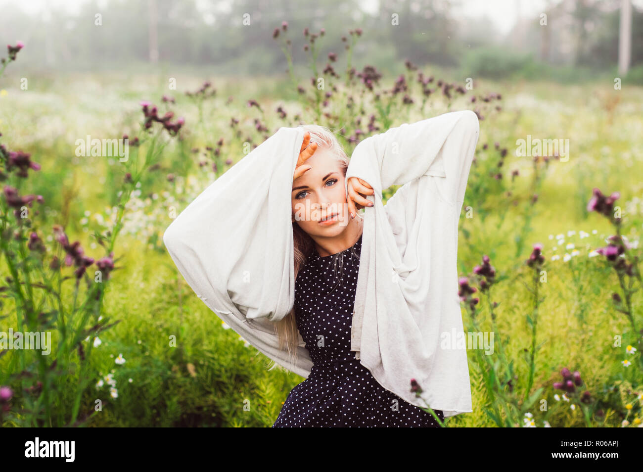 Portrait of young girl dancing in chamomile field with hands near face ...
