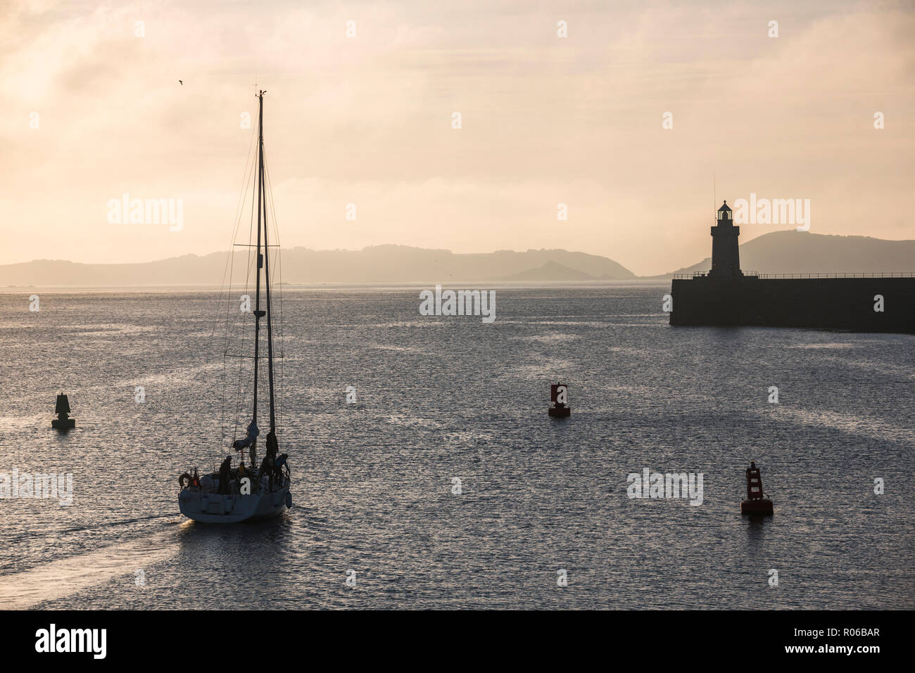 Sailing boat heading out of St. Peter Port Harbour at sunrise, Guernsey, Channel Islands, United Kingdom, Europe Stock Photo