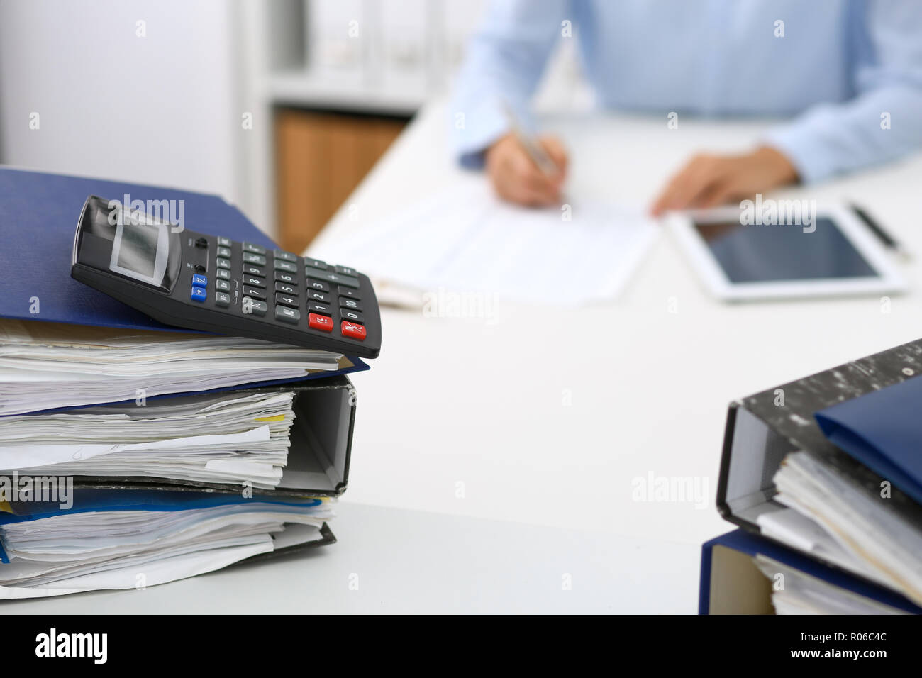 Calculator and binders with papers are waiting to be processed by ...