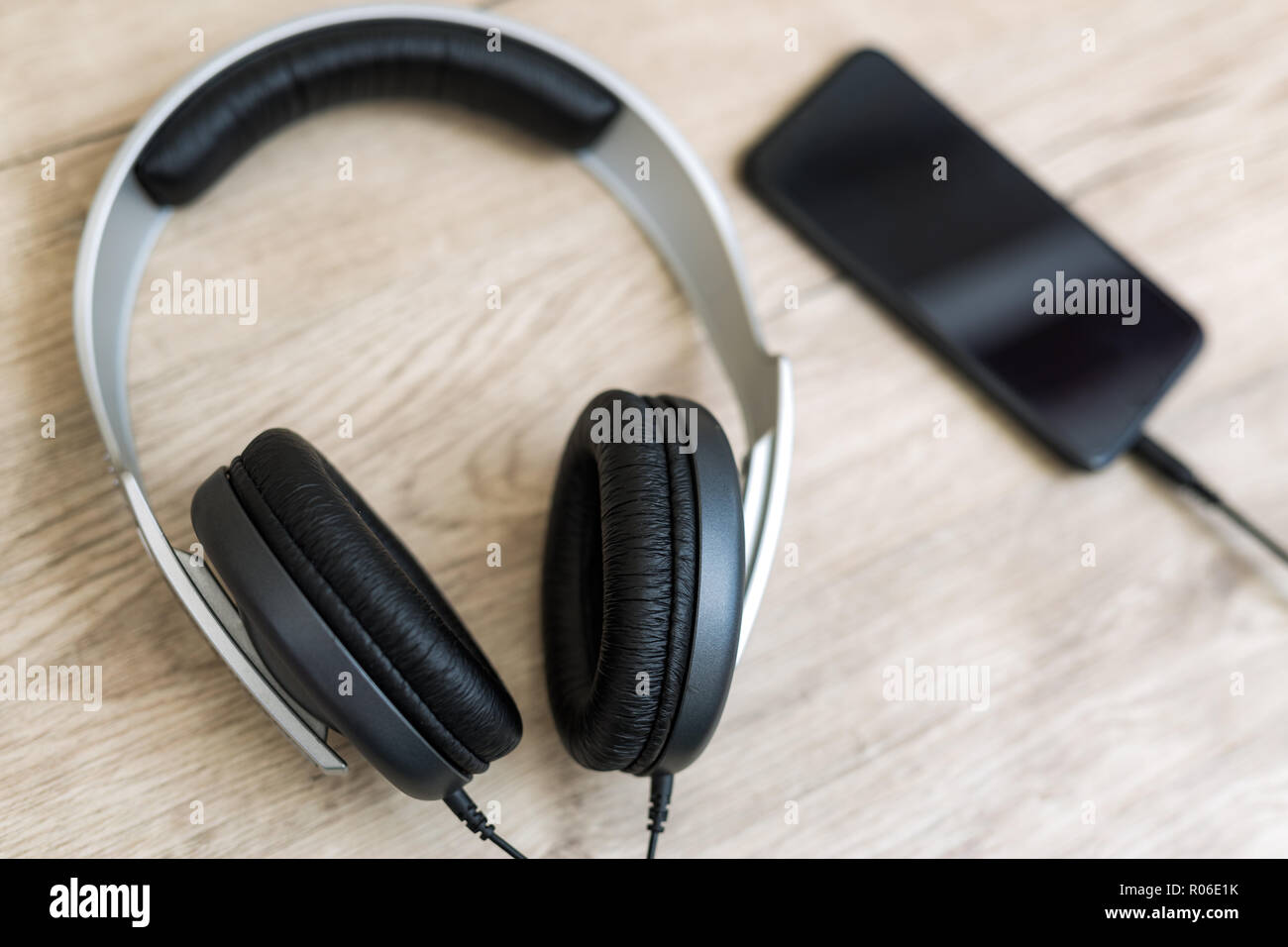 Smartphone with headphones on old wooden table. Modern technology music player. Stock Photo