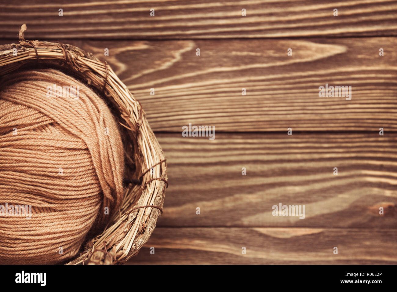 top view of brown woolen tangles of threads in wicker basket on wooden ...