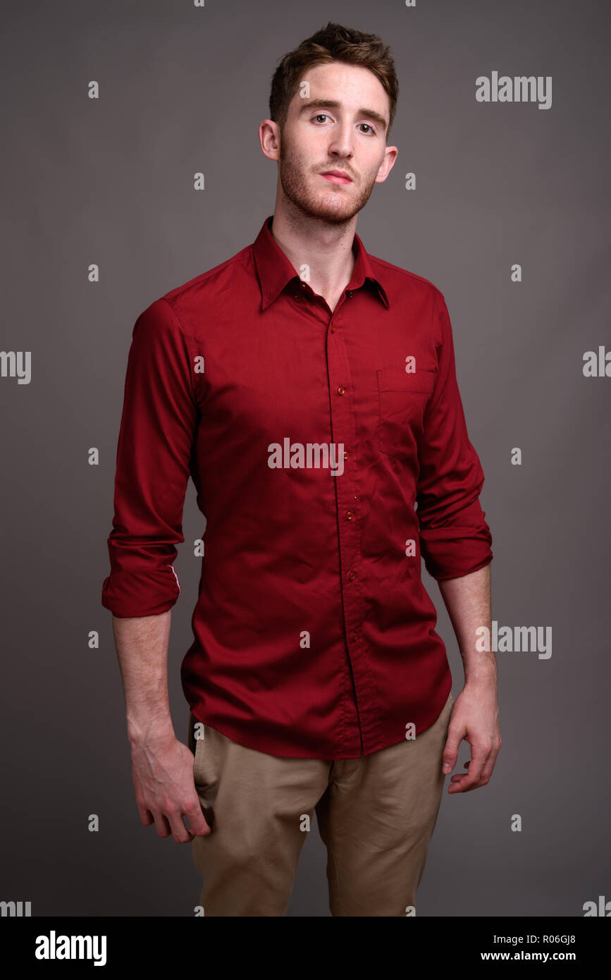 Young handsome businessman wearing red shirt against gray backgr Stock Photo