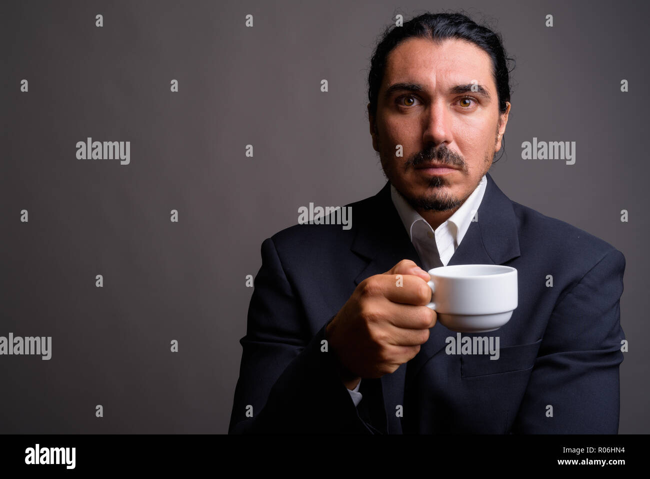 Handsome businessman with mustache wearing suit against gray bac Stock Photo