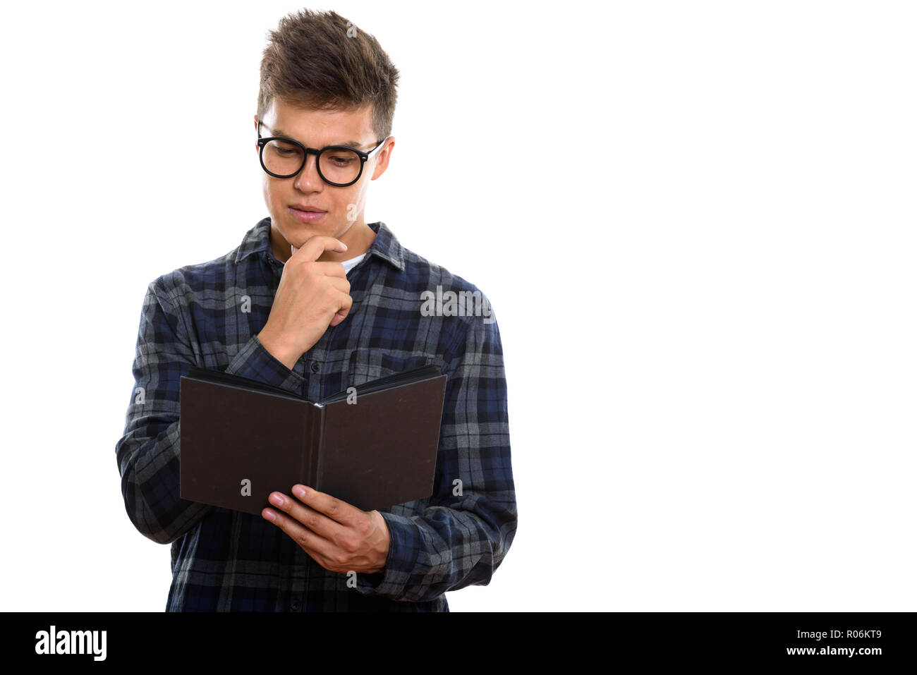Studio shot of young handsome man reading book while thinking Stock Photo