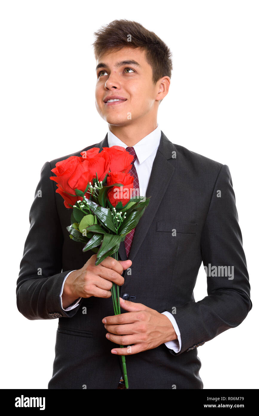 Thoughtful young happy businessman smiling while holding red ros Stock Photo