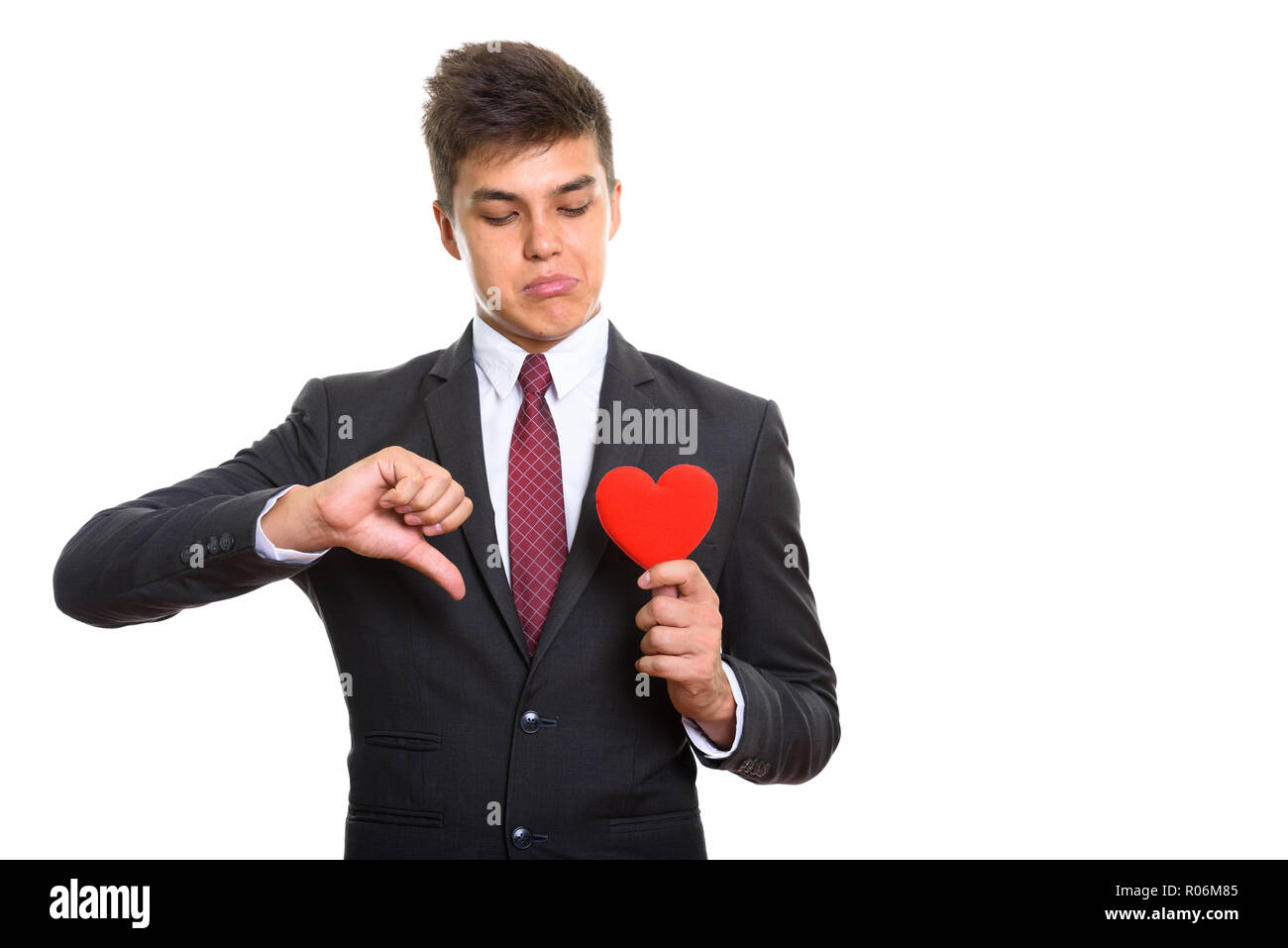 Young sad businessman giving thumb down while holding and lookin Stock Photo