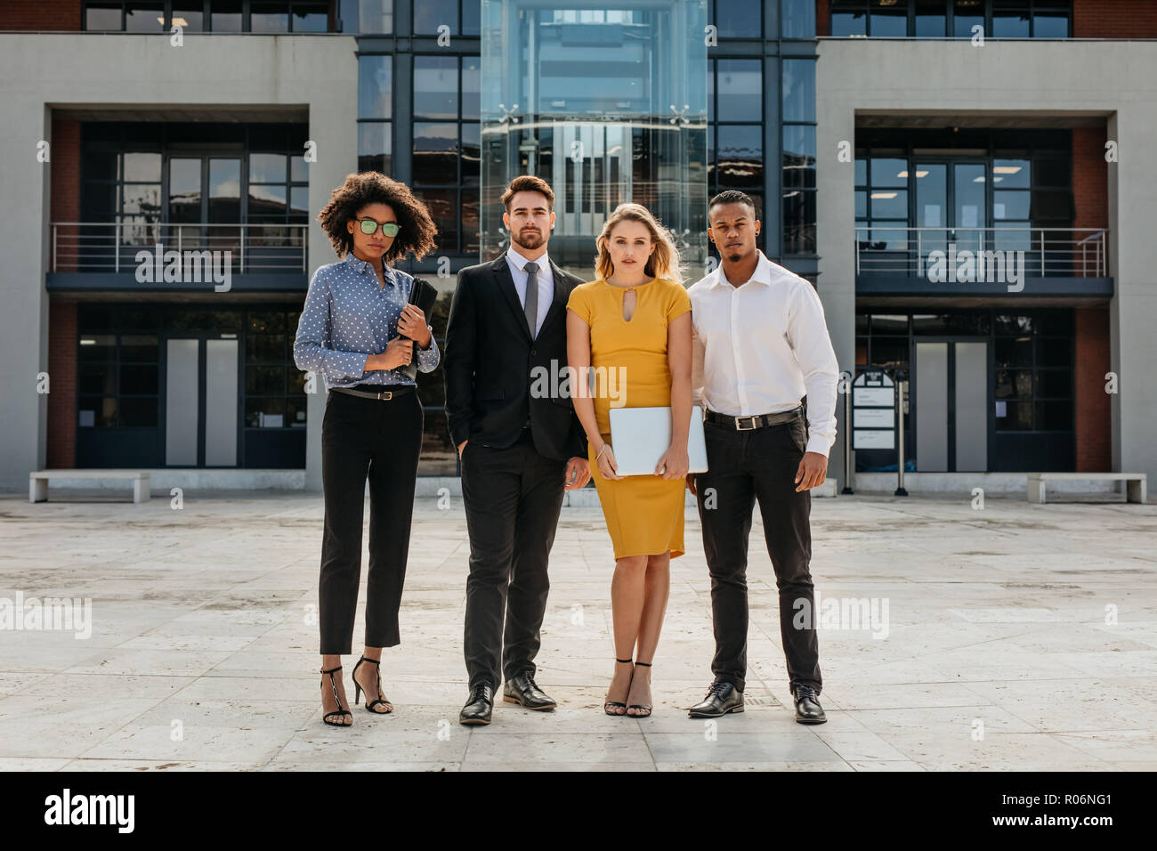 Full length of corporate professionals standing together in front a ...