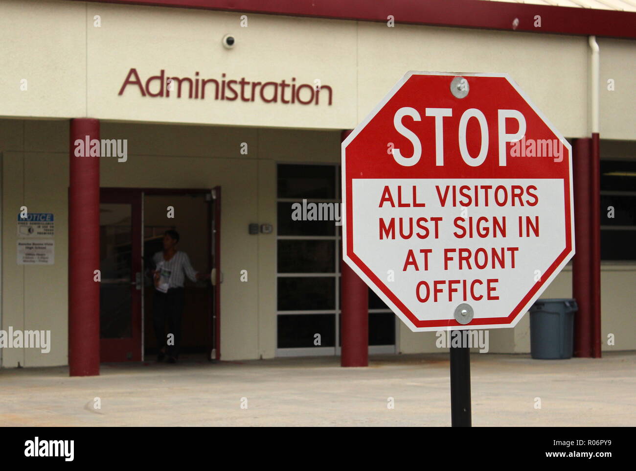 school security concept: a sign warns visitors of a high school that they need to sign in at the office Stock Photo